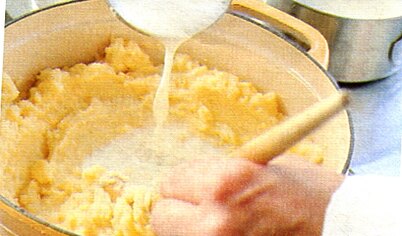 Масло добавьте в пюре, разделив его на части. Помешивайте деревянной ложкой. Вскипятите молоко и понемногу добавляйте в пюре.