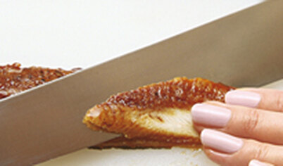 Держа нож наискосок относительно рыбы, нарежьте угря длинными ломтиками. Половину листа нори нарежьте тонкими полосками – они пригодятся, чтобы закреплять рыбу на рисе.