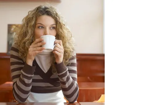 Девушка в полосатой кофте пьет кофе и худеет без диет и физических упражнений
