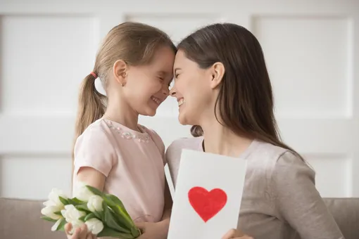 Мама с дочкой улыбаются и держат тюльпаны и сердечко Поздравления с 8 марта дочерям