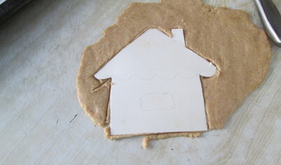 Раскатать тесто толщиной 0,5 см. По трафарету вырезать домик, формочками другие фигурки.