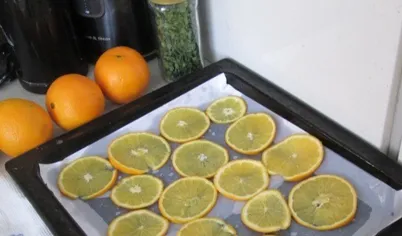 Застелить противень промасленной бумагой и разложить дольки апельсина.