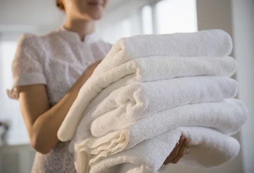 Девушка несёт чистые белые полотенца, стирка полотенец с уксусом в стиральной машине