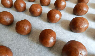Противень для выпечки застелить пекарской бумагой. Из теста скатать шарики размером с грецкий орех и выложить на противень. Духовку разогреть до 190 градусов и выпекать печенье 20 минут.