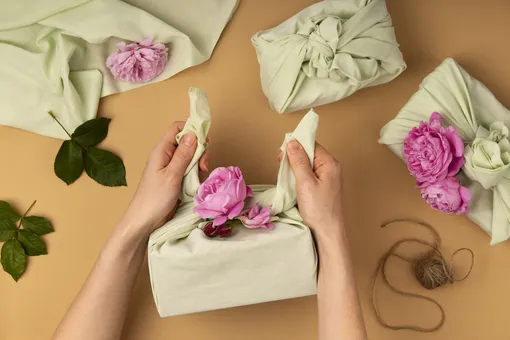 Вставьте в узелки цветы или веточки, чтобы дополнительно украсить подарок