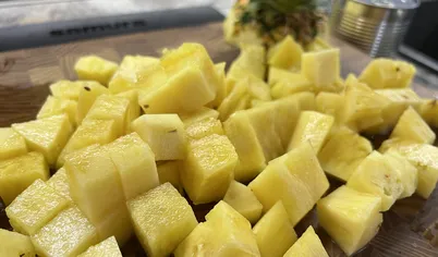 Очищаем ананас, вырезаем сердцевину и нарезаем мякоть на небольшие кубики.