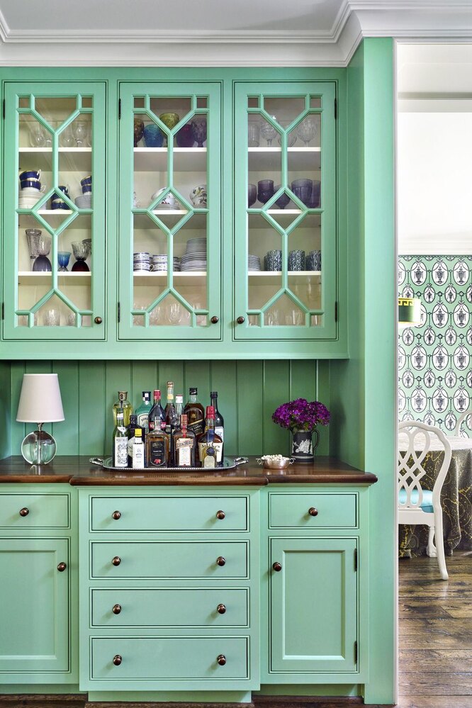 Цвет зеленого гарнитура сочетается с обоями на заднем плане кухни-столовой