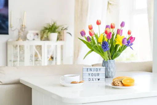 Ваза с тюльпанами на столе, кофе, печенье и карточка с пожеланием доброго утра и наслаждения днем
