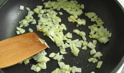 В это время, пока варится наша паста, обжариваем на большой сковороде на оливковом масле мелко нарезанный лук. Затем добавляем зубчики чеснока, нарезанные тонкими пластинками. Пассируем на среднем огне пару минут.