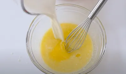 Размягченное сливочное масло разотрите со 150 г сахара. Добавьте молоко и яйца. Взбейте все ингредиенты венчиком.