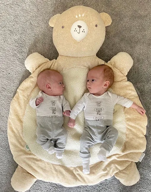 Новорожденные близнецы лежат на коврике