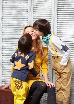 два ребенка целуют сидящую мать