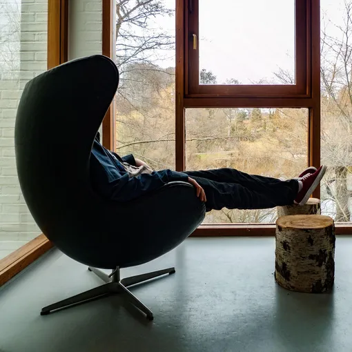 Мужчина отдыхает в кресле-яйце у окна