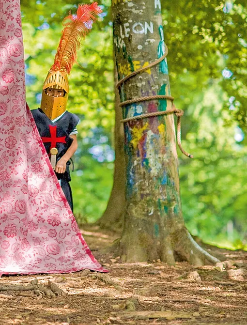 Мальчик в костюме рыцаря за деревом