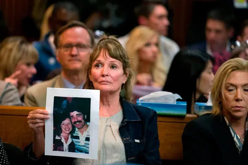 Мелани Барбо держит фотографию жертв Чери Доминго и Грега Санчеса во время предъявления обвинения Джозефу Джеймсу Де Анджело