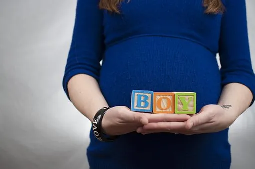 беременная женщина держит перед животом кубики с буквами