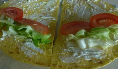 На смазанную сыром лепешку выложить капусту и дольки помидора
