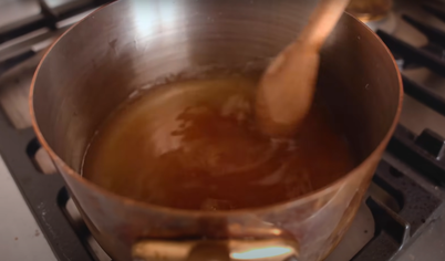 Пока пахлава готовится в духовке, приготовьте соус. В сотейник засыпьте сахар, налейте воду. Поставьте на плиту и подождите, пока сахар растает. Добавьте ваниль и мёд. Варите около 20 минут.