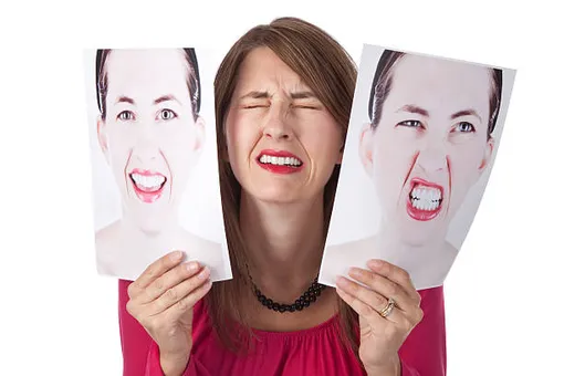 женщина держит две картинки по обе стороны лица — веселая, сама плачет, злая