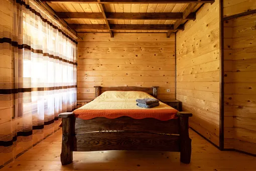 Спальня в деревенском стиле с двуспальной деревянной кроватью