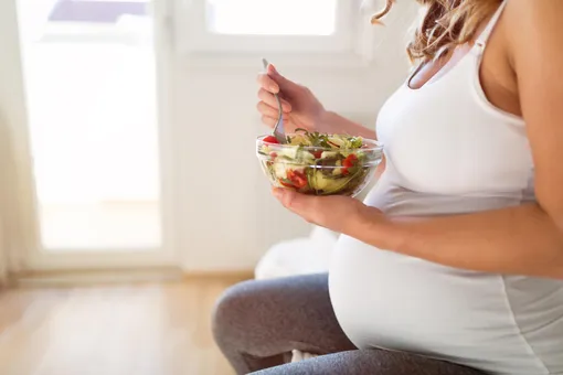 Беременная женщина ест салат