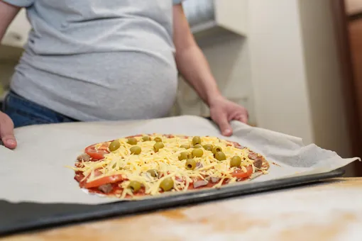 Беременная женщина готовит пиццу