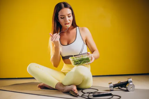 Девушка ест салат после занятий спортом, безуглеводная диета для похудения