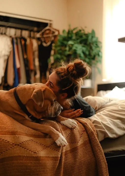 Девушка лежит на кровати с собакой