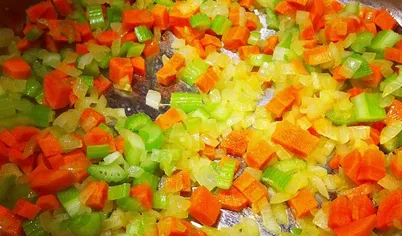 Нарежьте кубиками лук, морковь и сельдерей и положите их в кастрюлю. Добавьте соль. Обжаривайте около 8 минут, периодически помешивая. Добавьте томатную пасту. Перемешайте.
