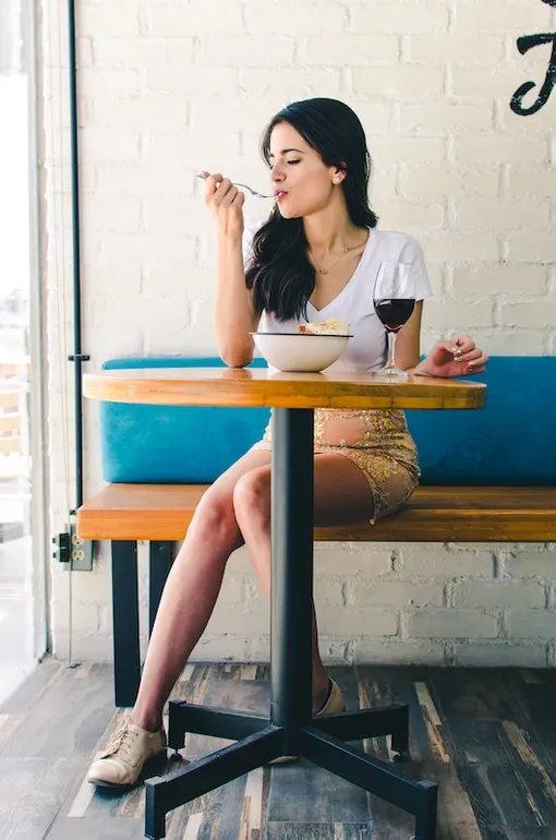 Девушка в кафе ест и смотрит в окно
