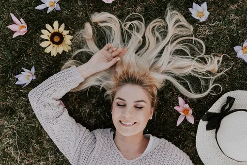 Девушка разложила светлые волосы по траве с цветами