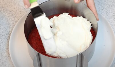 Теперь давайте собирать торт «Красный бархат». Положите корж в форму, но если ее у вас нет, подойдет  плоская тарелка. Промажьте его как следует половиной крема. Сверху положите второй корж и равномерно распределите по нему вторую половину крема, а потом посыпьте крошками, измельченными в блендере. Если вы хотите покрыть торт кремом по бокам, то разделите крем на три части. Но право же, он выглядит гораздо ярче и нарядней с «голыми», ярко-красными боками и белой прослойкой крема между коржами. Украсить торт можно по своему вкусу.
