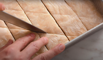 Ножом нарежьте тесто на квадраты или треугольники. Поставьте в духовку и выпекайте около 50 минут, пока пахлава не станет золотистой и хрустящей.