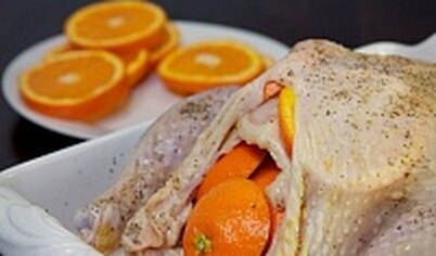 Аккуратно поднимите кожу на грудке курицы и проложите апельсиновые кружки между мясом и кожей. Переверните курицу и сделайте то же самое на спине.