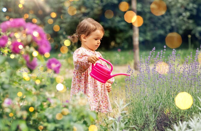 девочка поливает лейкой цветы