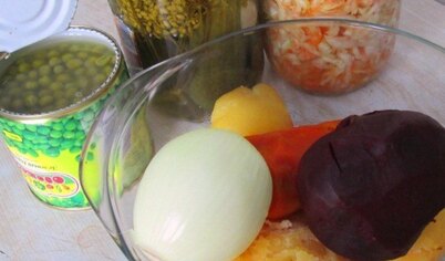 Нарежьте остывшие овощи, огурцы, лук. Добавьте зеленый горошек и квашенную капусту.