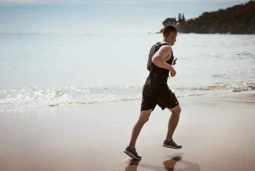 мужчина бежит по пляжу