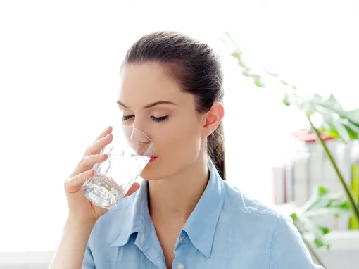 Девушка пьёт воду, чтобы избавиться от неприятного запаха изо рта