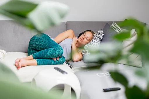 Женщина в лосинах дремлет на диване