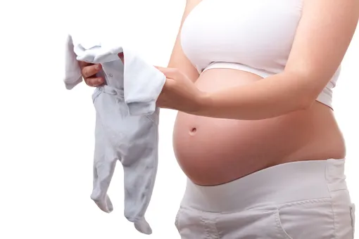 Беременная женщина держит в руках ползунки