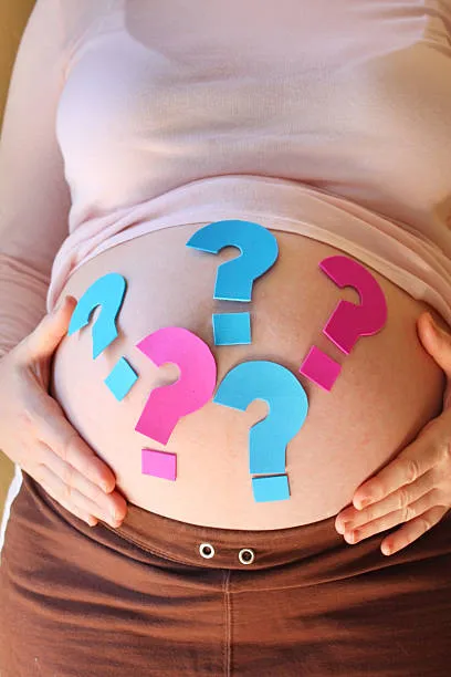 обнаженный живот беременной женщины с разноцветными знаками вопроса на нем