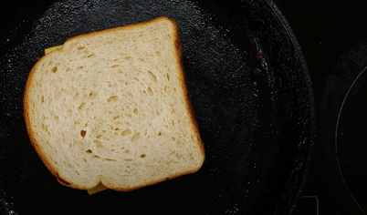 Смазываем маслом второй ломтик хлеба. Кладём его на сыр так, чтобы сторона с маслом была сверху.
