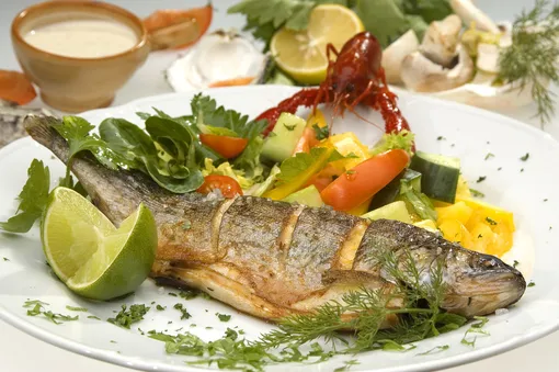 Запеченная рыба с зеленью и наймом на тарелке, систем питания «Три кулака»