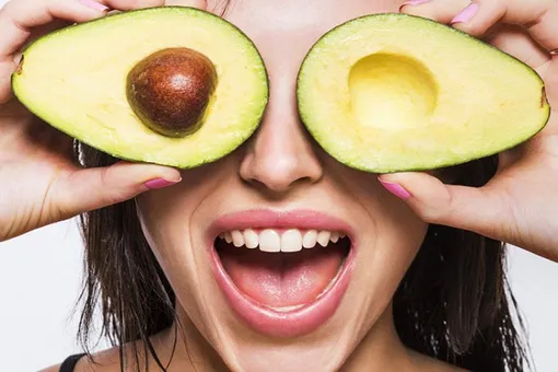 Девушка загораживает глаза половинками авокадо, продукт против старения