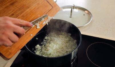 Чистим и мелко нарезаем лук и чеснок. Ставим на плиту сотейник и разогреваем в нём сливочное масло. Когда масло разогреется, пассируем (жарим до выпаривания сока) лук и чеснок 1 минуту.
