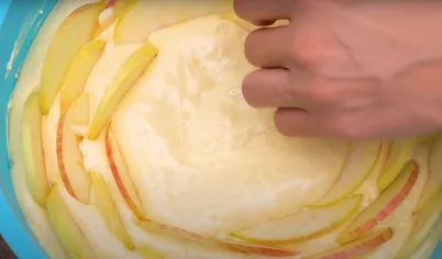 Форму для выпекания шарлотки выстелите пекарской бумагой, смажьте сливочным маслом и присыпьте мукой. Вылейте половину теста и разровняйте. Выложите половину яблок: двигайтесь от бортиков по спирали к центру. Оставшееся тесто и яблоки выложите аналогичным способом. Посыпьте корицей.
