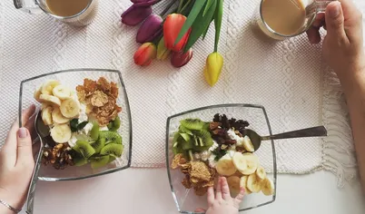 Порезать фрукты, на тарелку выложить по центру творог, вокруг положить орехи, хлопья, банан и киви. Вкусно, полезно и просто!