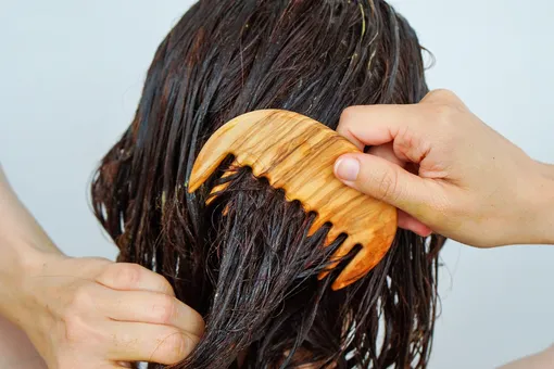 Девушка расчесывает мокрые волосы