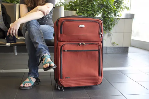 девушка рядом с чемоданом в аэропорту