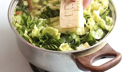 Выложите в суп нарезанный шпинат и савойскую капусту, перемешайте, чтобы зелень осела, добавьте корочку пармезана. Варите суп примерно 40–50 минут. Подавайте с натертым пармезаном или с соусом песто.